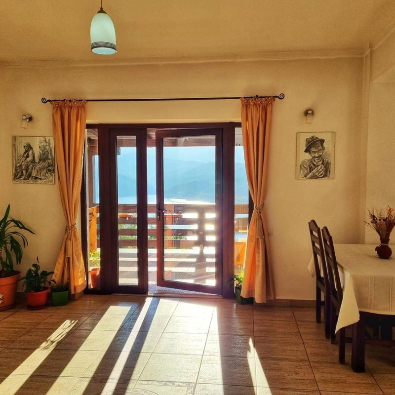 Ușă spre balcon, cu lumina dimineții și vedere spre lac