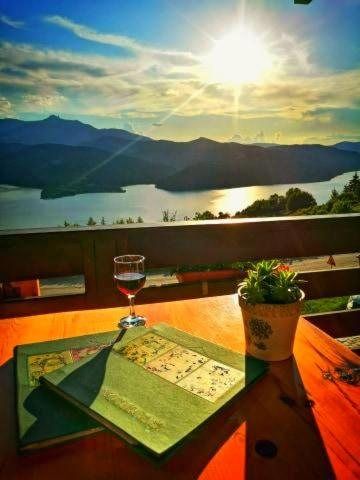 Masă pe terasă la apus, cu un pahar de vin și vedere spre lac