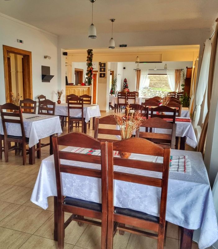 Sala restaurantului, cu mese și scaune din lemn și fețe de masă albe
