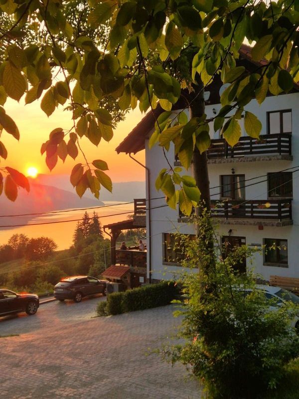 Apus de soare lângă pensiune, văzut printre frunze